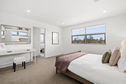 珀斯Modern Minimalistic Home 3BR的一间卧室配有一张床、一张书桌和一面镜子