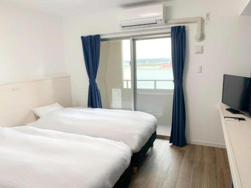 冲绳岛市Villa Awase 111 - Vacation STAY 21909v的配有窗户的酒店客房内的两张床