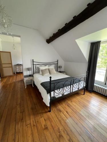 维尔法格Château de Villefargeau的一间卧室配有一张床,铺有木地板