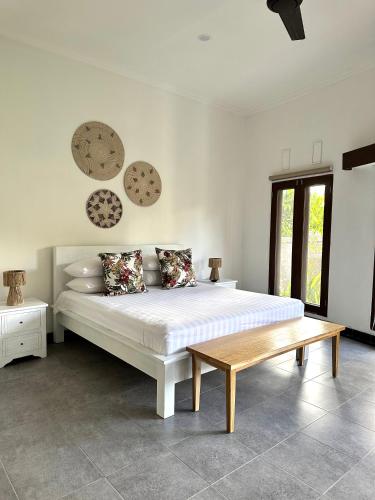 乌鲁瓦图Asri Villas Bingin的卧室配有白色的床和木板凳