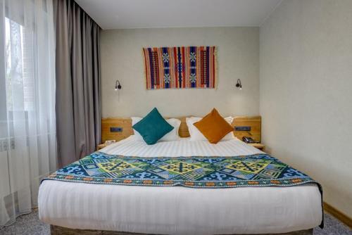 比什凯克My Hotel Bishkek的一间卧室配有一张带色彩缤纷枕头的大床