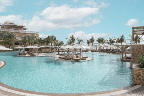 迪拜Wyndham Residences The Palm的度假村的游泳池配有椅子和遮阳伞
