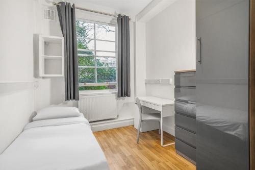 伦敦Bowden Court (Notting Hill)的一间卧室设有两张床、一张桌子和一个窗口。