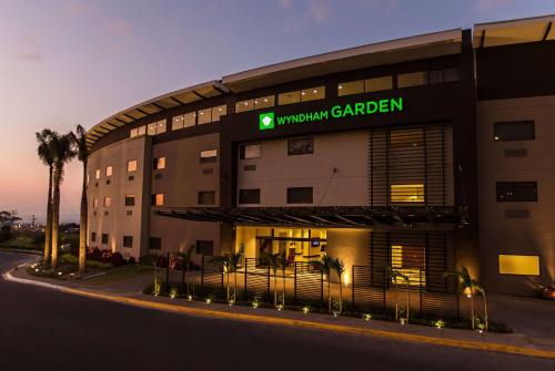 圣何塞Wyndham Garden San Jose Escazu, Costa Rica的带有读大学花园标志的酒店大楼