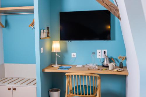 AltillacCueillette的一间设有一张桌子的房间,在蓝色的墙上配有电视