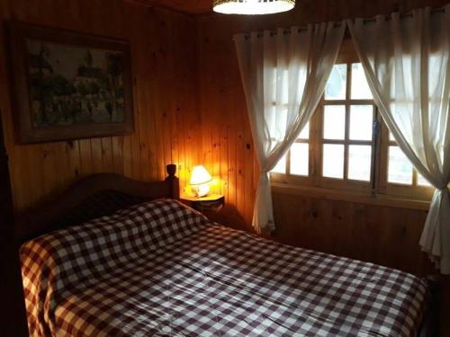 波特雷里约斯Cabaña Familiar El Refugio的一间卧室配有一张带 ⁇ 子毯子的床和窗户