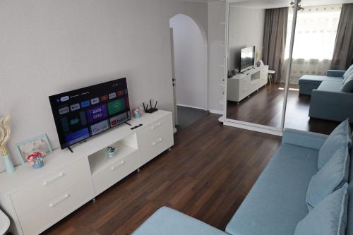 卡拉甘达Люкс в центре Караганды的客厅配有电视和蓝色沙发。