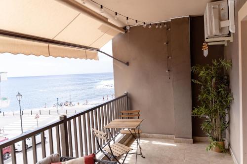 巴耶格兰雷伊Casa Arjuna的阳台配有桌椅,享有海滩美景。