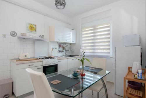 乌马格Seafront Apartment Jadri的厨房配有玻璃桌和白色家电
