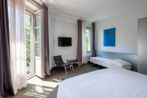 卢塞恩大陆公园酒店的一间卧室配有一张床、一把椅子和窗户。