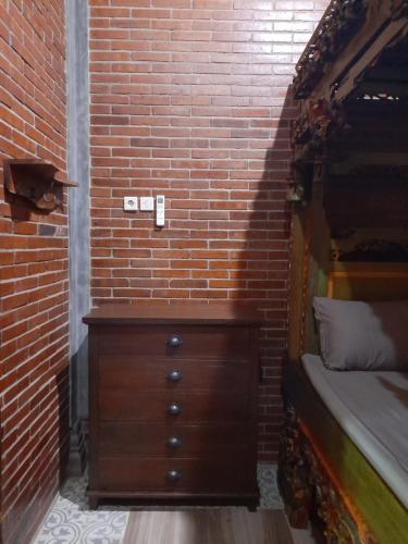 KaranganyarKrobyongan staycation kalaras的一间卧室设有木制梳妆台和砖墙