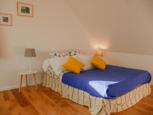 洛克马里亚Maison Locmaria, 3 pièces, 6 personnes - FR-1-418-209的一间卧室配有一张带蓝色床单和黄色枕头的床。