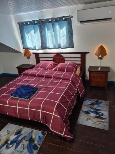 SinnamaryRésidence JB的一间卧室配有一张带红色拼盘床罩的床