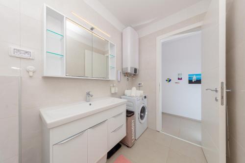 班约勒Apartman Adoria的白色的浴室设有水槽和洗衣机。