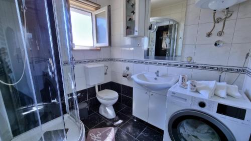 杜埃Black and White Apartment - 2 bedrooms, walk to the beach的浴室配有卫生间水槽和洗衣机。