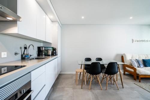 蒙蒂戈杜Coastal Holiday´s Apartment的厨房配有白色橱柜和桌椅