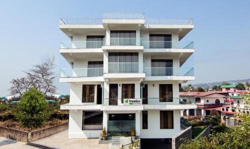 达兰萨拉Treebo Trend Ortus Residency的白色的建筑,旁边设有阳台