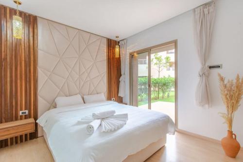 马拉喀什Résidence Golfique PJ, jardin, piscine的卧室配有白色的床,上面有弓