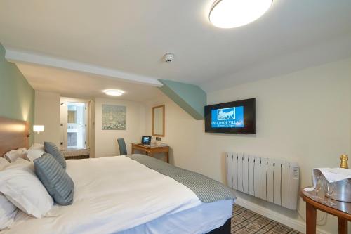 博尔顿最后一滴水乡村Spa酒店的卧室配有白色的床,墙上配有电视