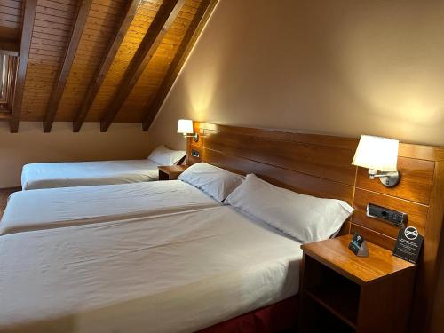 拉林Hotel Alda Lalín的配有2盏灯的酒店客房的2张床