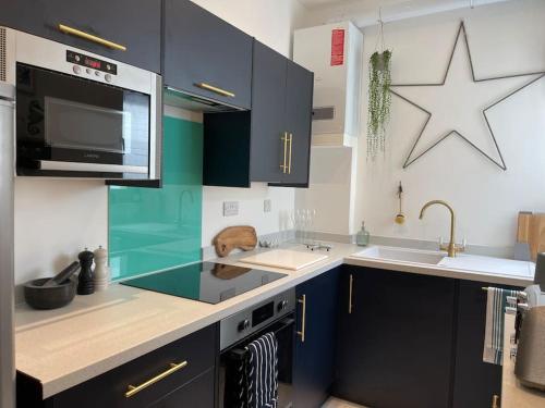 文特诺Top Deck - Fresh, stylish seaside apartment的厨房配有蓝色橱柜,墙上有一颗星星