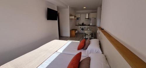 穆希亚Estudios en Plaza Cabo da Vila centro Muxia的一间卧室配有一张带橙色枕头的大床