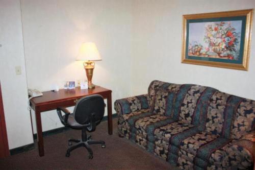 琼斯伯勒ARK SUITES的酒店客房配有沙发、书桌和椅子