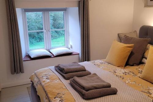 WhitwellFossil Cottage (Berryl Farm Cottages)的一间卧室配有一张床,上面有两条毛巾