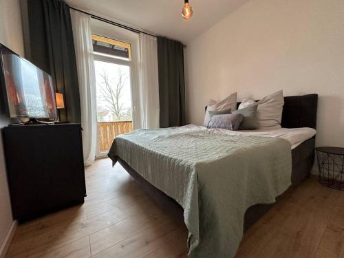 阿尔滕堡Herrliches wohnen mit Teichblick的一间卧室配有一张床、一台电视和一个窗口