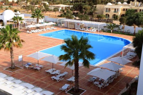 DjerbaHotel Riad Meninx Djerba的享有带椅子和遮阳伞的游泳池的上方景致