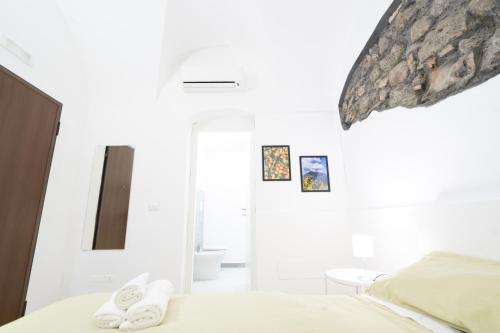 卡塔尼亚Be happy Rooms的卧室拥有白色的墙壁,配有带拖鞋的床铺。
