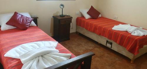圣奥古斯汀镇La Soñada de La Majadita的一间设有两张红色和白色床单的房间