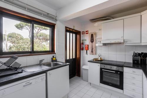 维拉摩拉Home Out Vila do Lince - 8 Bedrooms, Heated Pool & Gym - Marina Vilamoura的厨房配有白色橱柜、水槽和窗户。