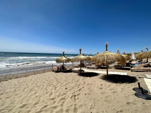 马贝拉El Arenal Townhouse By The Beach With Swimming Pool - EaW Homes的一片带一些草伞和海洋的海滩