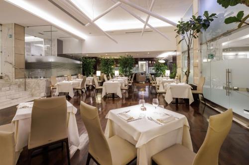 罗马环球贝斯特韦斯特优质酒店的一间设有白色桌椅的用餐室