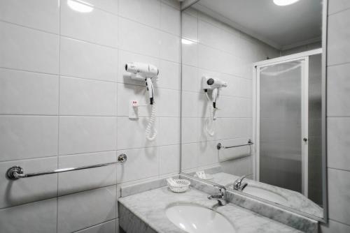 瓦尔迪维亚Hotel Melillanca的一间带水槽和淋浴的浴室以及一部电话