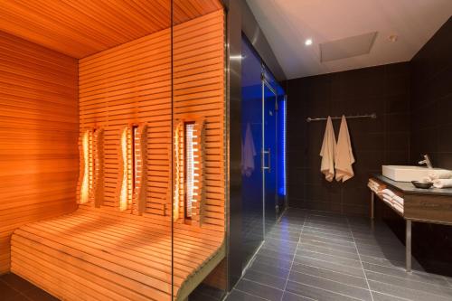 海牙Leonardo Royal Hotel Den Haag Promenade的带淋浴的浴室和木墙