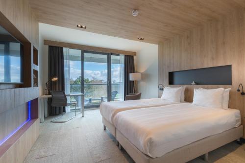 海牙Leonardo Royal Hotel Den Haag Promenade的酒店客房设有一张大床和一张书桌。
