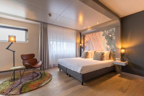 阿尔梅勒Leonardo Hotel Almere City Center的配有一张床和一把椅子的酒店客房