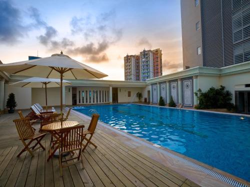 珠海珠海来魅力假日酒店-拱北口岸店的一个带桌椅的游泳池以及遮阳伞