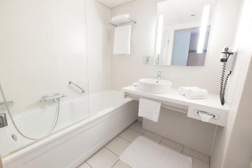 布雷达Leonardo Hotel Breda City Center的白色的浴室设有水槽和浴缸。