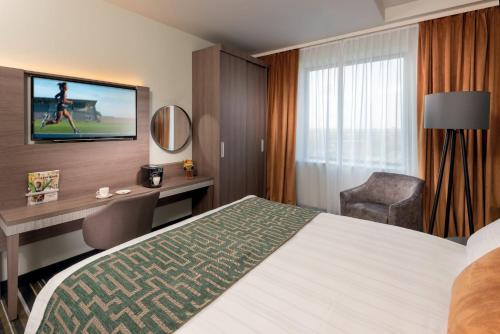 阿姆斯特丹Leonardo Royal Hotel Amsterdam的酒店客房配有一张床、一张书桌和一台电视。