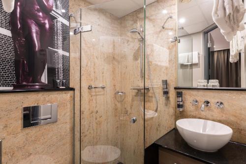 阿姆斯特丹Leonardo Boutique Museumhotel的一间带玻璃淋浴和水槽的浴室