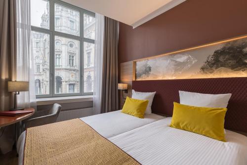 安特卫普莱昂纳多酒店安特卫普酒店的酒店的客房 - 带黄色枕头的床和窗户