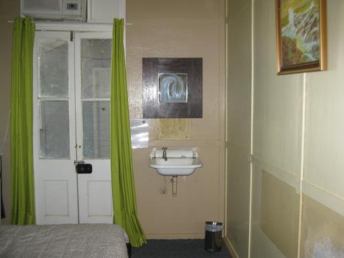 温顿Australian Hotel Winton Budget Hotel Accommodation的一间带水槽的浴室和一个带绿色窗帘的窗户