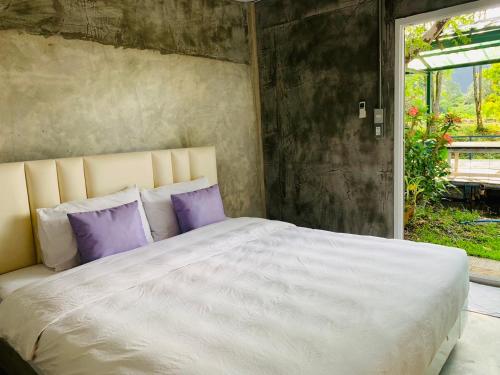 Ban Wang Takhraiปานีวิลล์ รีสอร์ต的卧室配有一张带紫色枕头的大型白色床。
