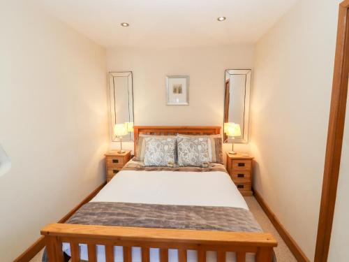 彭里斯Swallow's Nest的一间卧室配有一张木床和两盏灯。