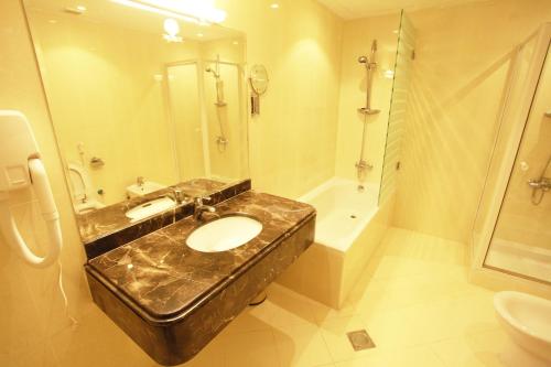 多哈金色海滨酒店的浴室配有水槽、淋浴和浴缸。
