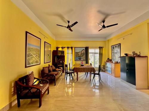 古瓦哈提Three Little Birds Homestay的客厅设有黄色的墙壁和桌椅