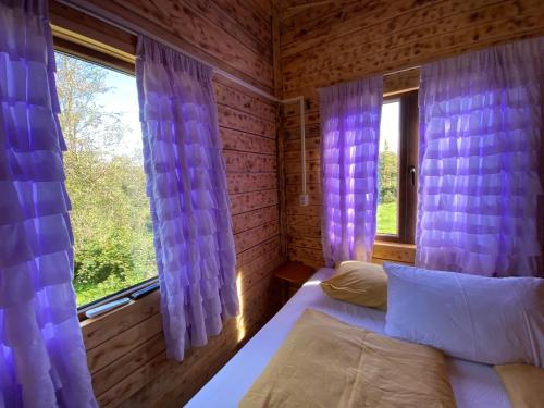 CărbunariLa Padurea Mica的一间卧室配有一张床和一个带紫色窗帘的窗户